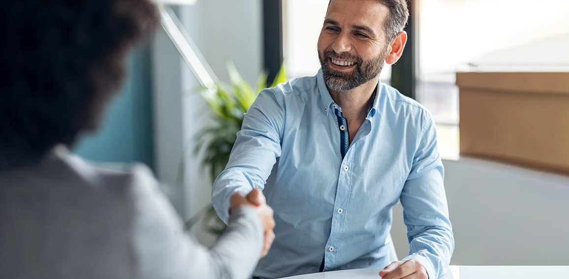 Attractive real-estate agent shaking hands with young couple aft