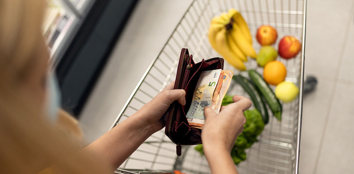 Worried woman checking her wallet when shopping in supermarket. Inflation and economic recession concept.