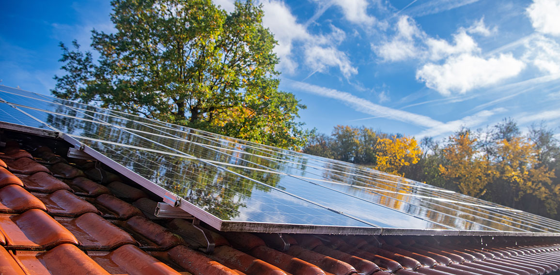 Wet photovoltaic modules in front of blue and cloudy autumn sky