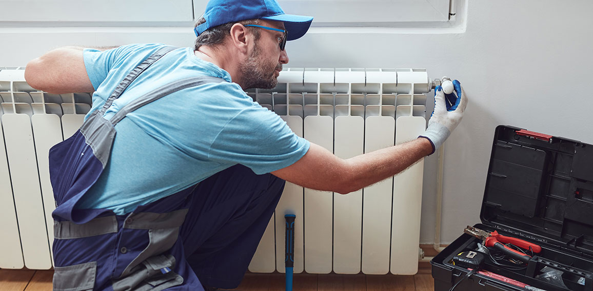 Central heating mechanic and handyman fixing home radiator, gas