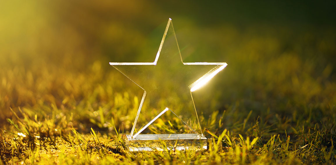 Transparent five-pointed star made of glass on a green summer ba