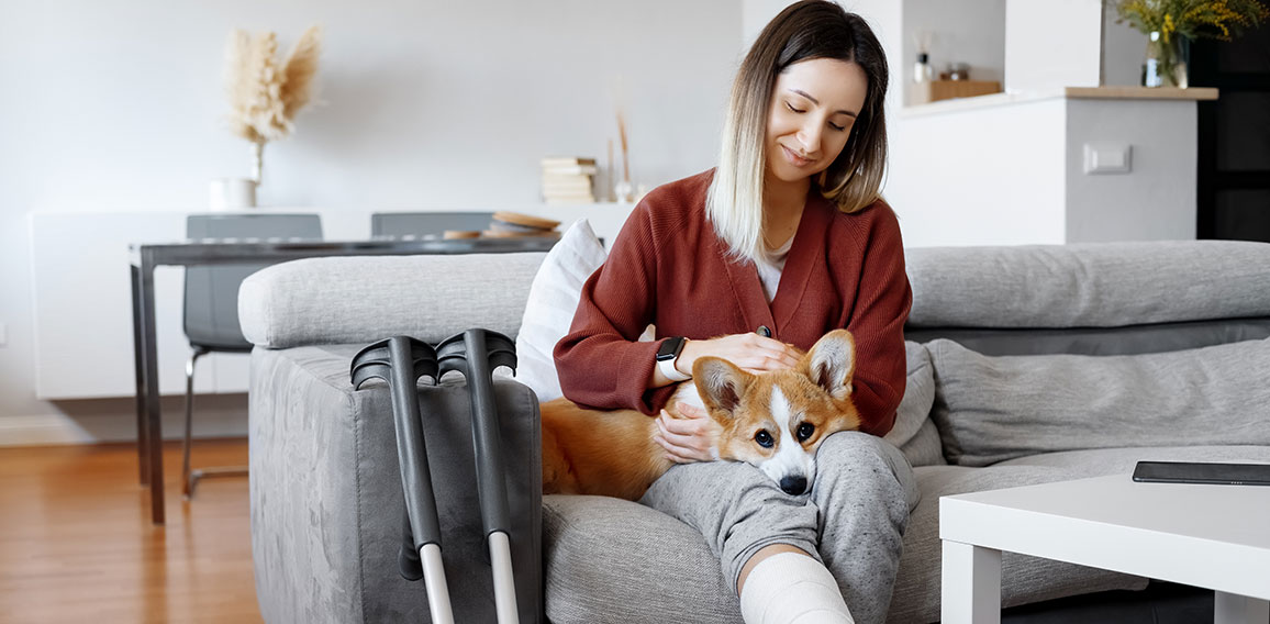 Adult woman in her late twenties on couch at home with crutches