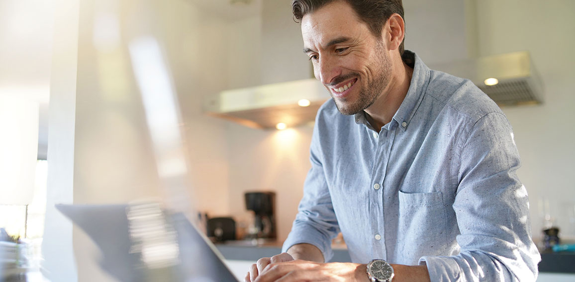 Handsome man with computer in modern kitchen