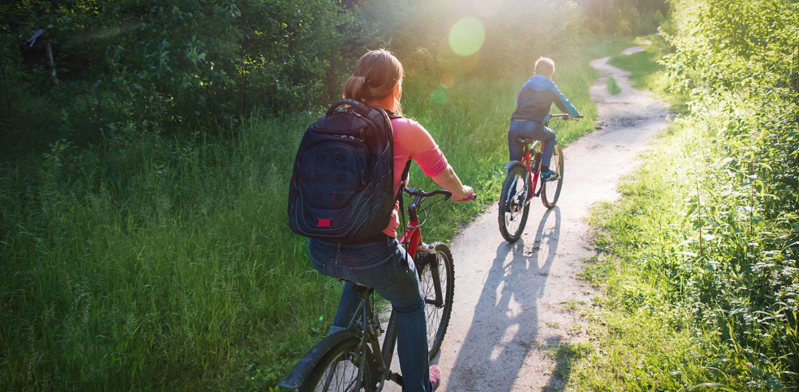 mother and son riding bikes in sunset nature