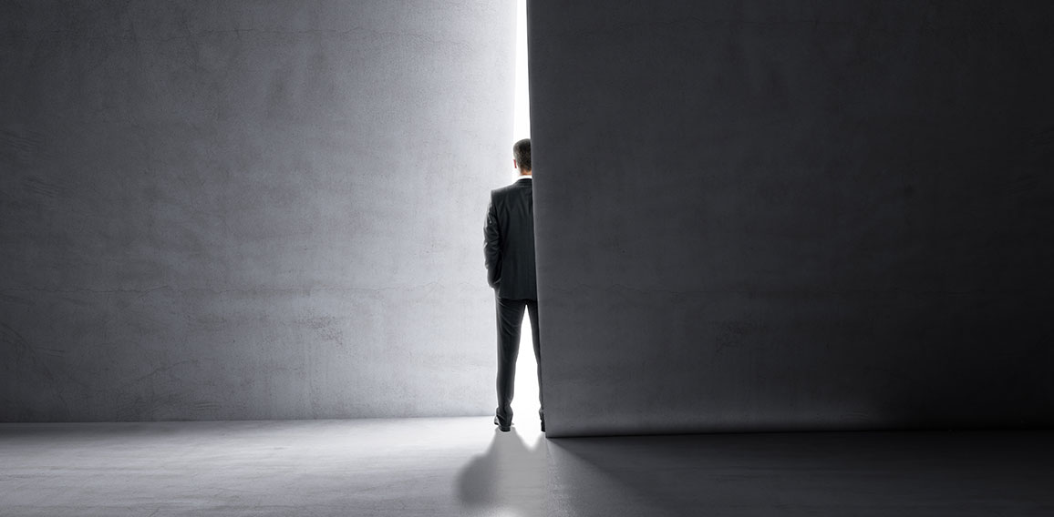 Back view of man stepping into the light from behind a concrete wall. Success and future concept.