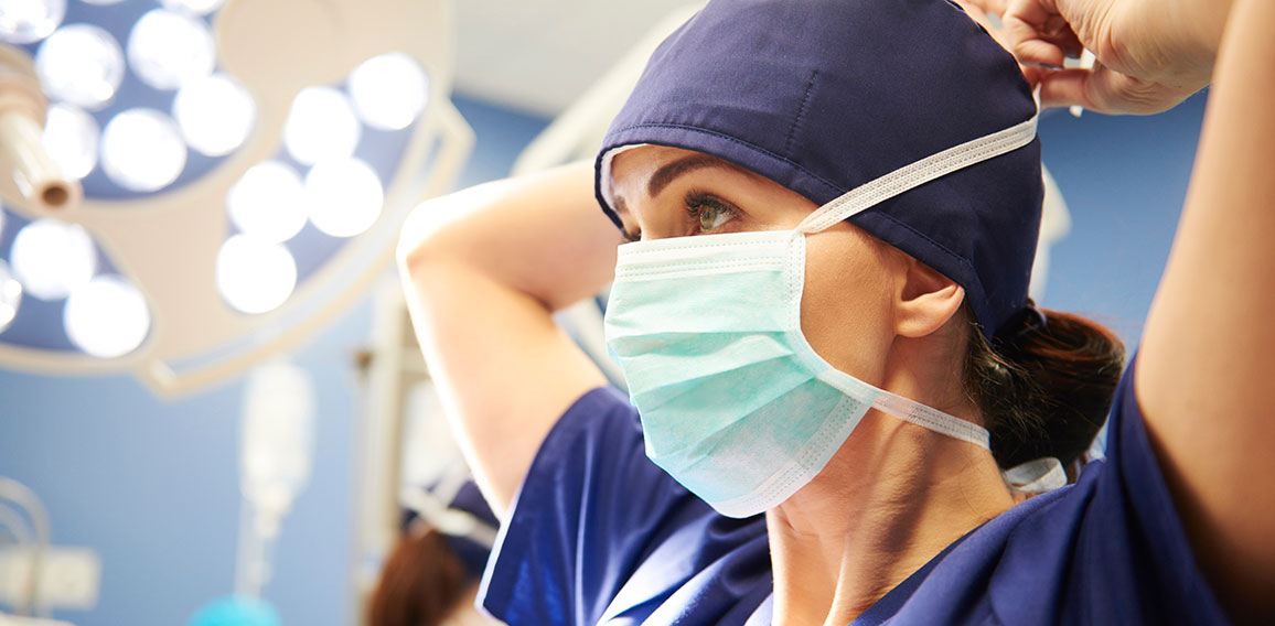 Side view of young female surgeon tying her surgical mask