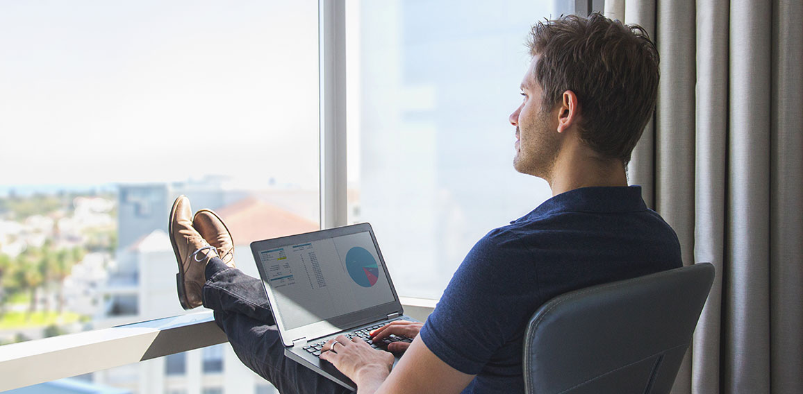 Young businessman in casual attire working on laptop at home off