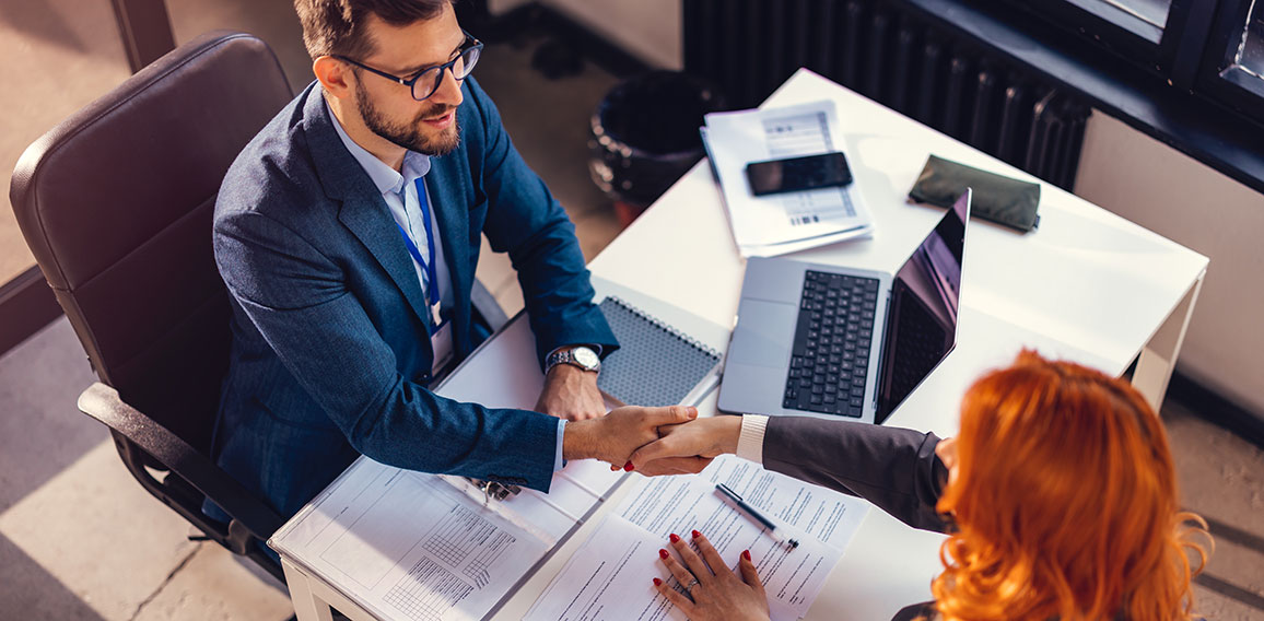 Happy bank manager shaking hands with a client after successful agreement in the office.