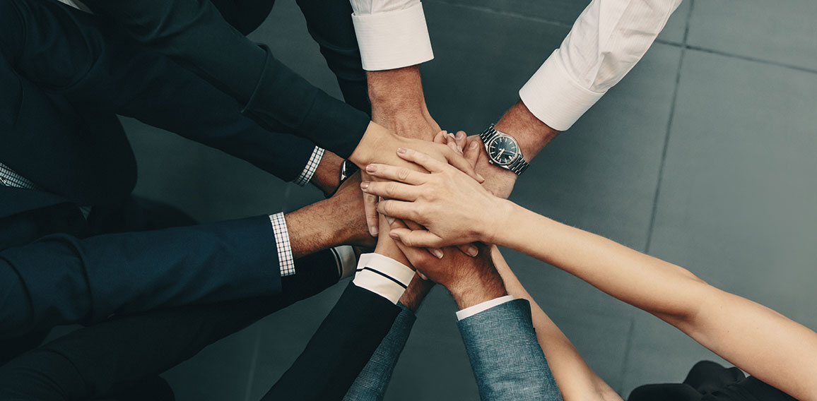 Diverse business team putting their hands together in a huddle of support and motivation