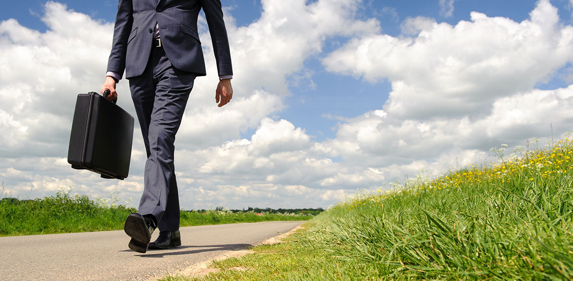 Young businessman walking a pathway in nature with green grass a