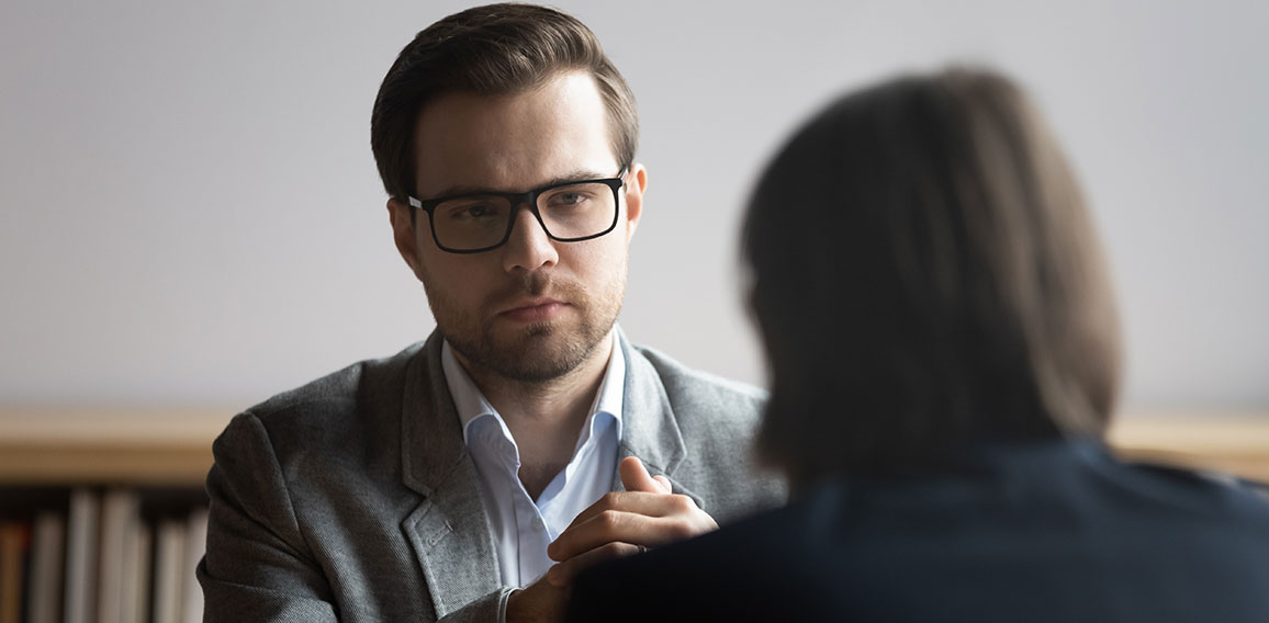 Concentrated male hr manager in glasses listening to job candidate.