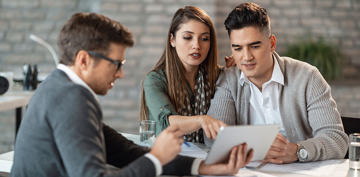 Young couple and financial advisor going through investment plans on digital tablet.