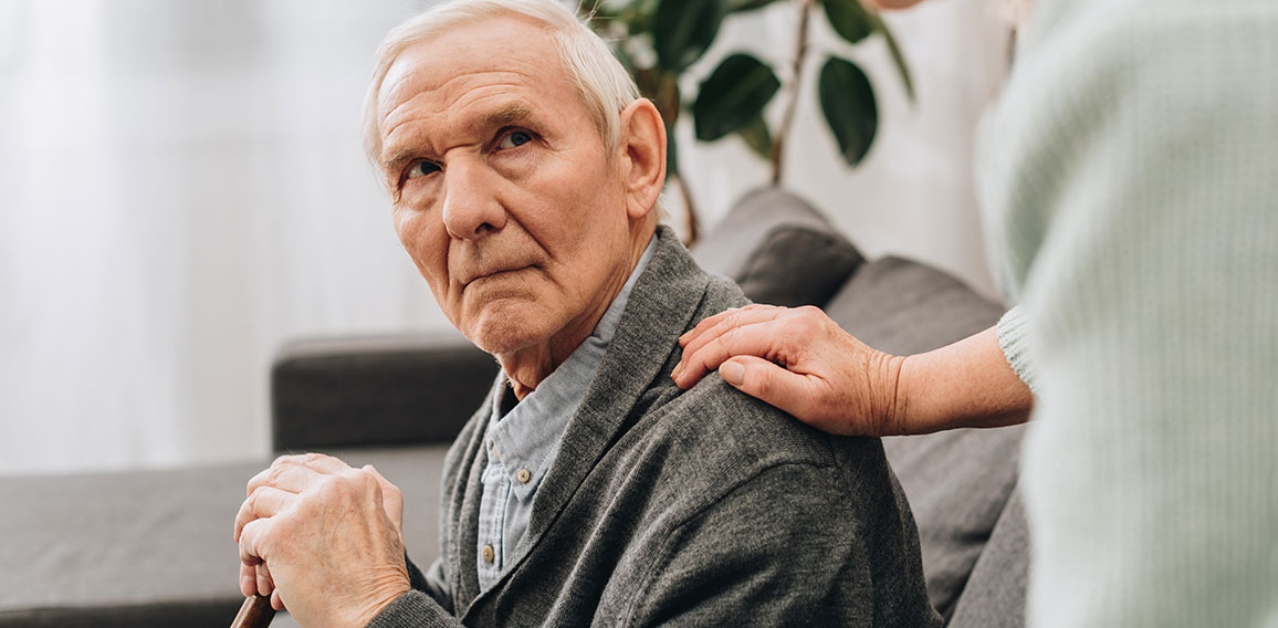 upset retired husband sitting in living room and looking at seni