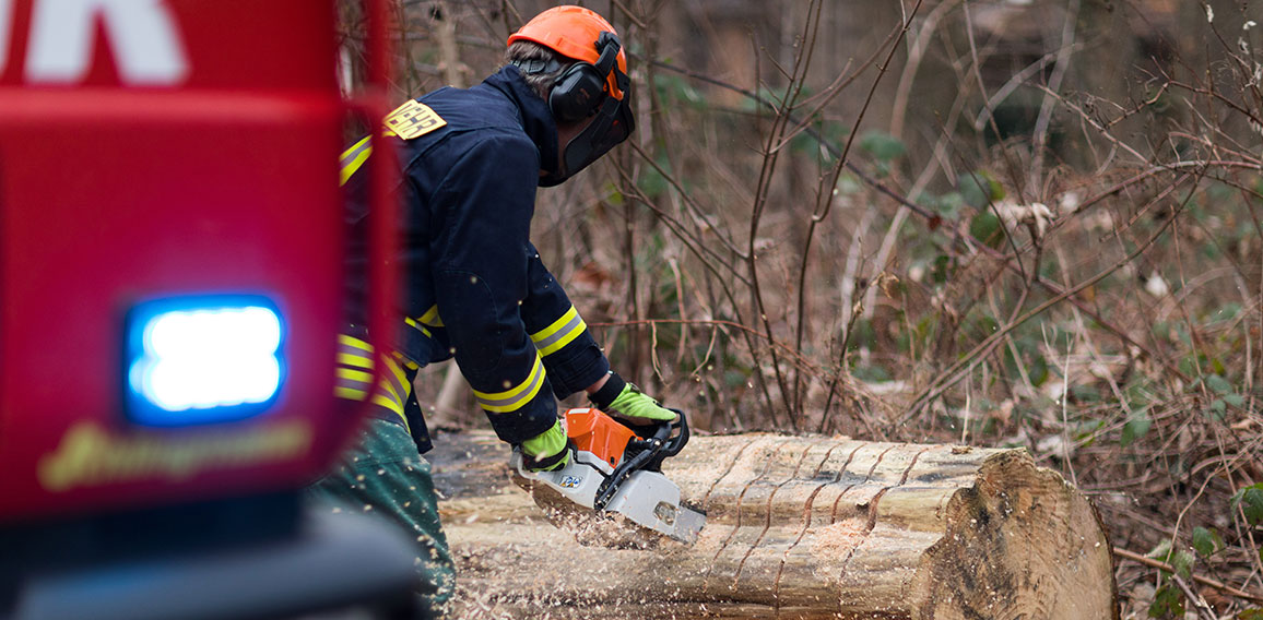 Feuerwehrmann mit Kettensäge beseitigt Sturmschaden