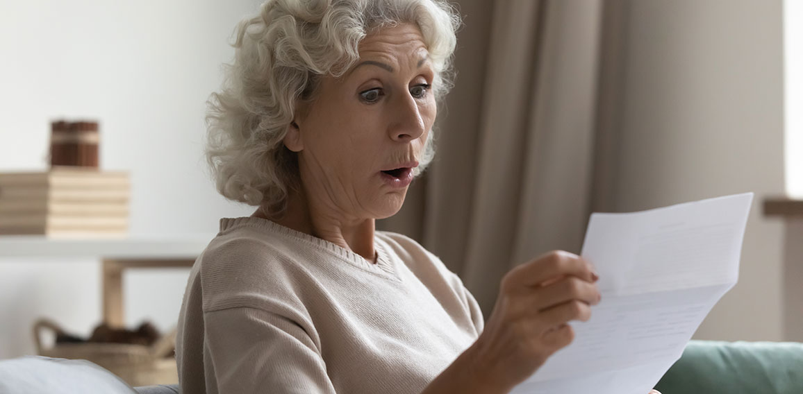 Amazed shocked mature woman with open mouth reading letter