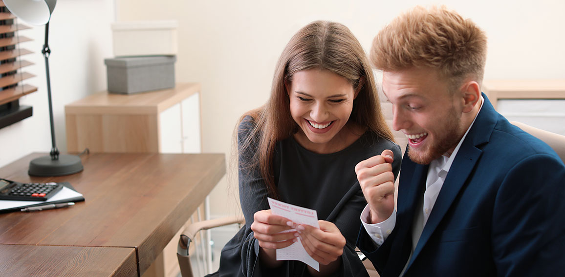 Happy young people with lottery ticket in office