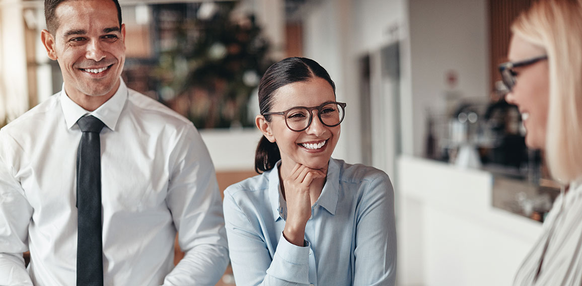 Three smiling coworkers talking together in an office