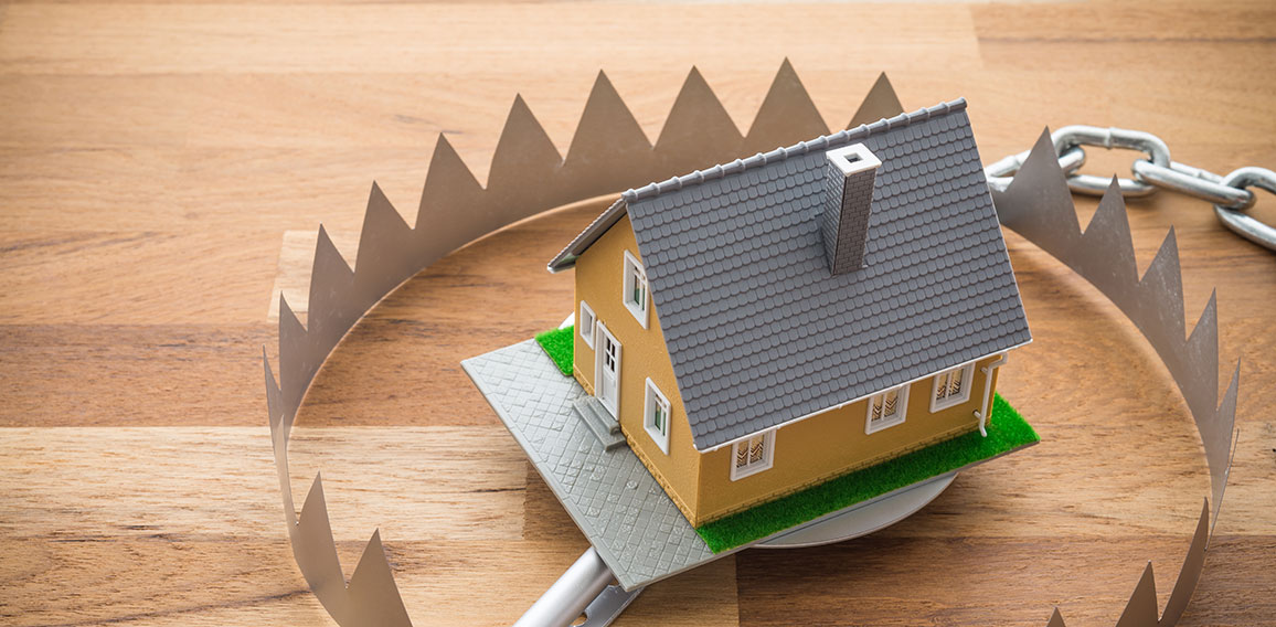 Mortgage house in a trap on wooden table background. House trap