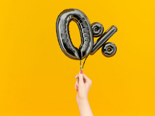 Female hand holding Zero percent symbol. 0 % banner black flying foil balloons on yellow. 3d rendering.