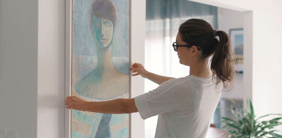 Woman hanging a painting at home