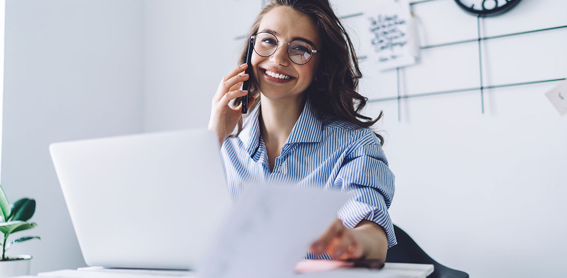 Young woman laughing while talking on cellphone in office