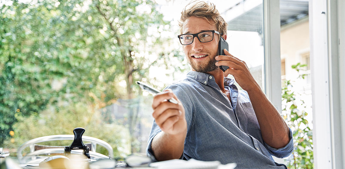 Casual young businessman on the phone at desk in office