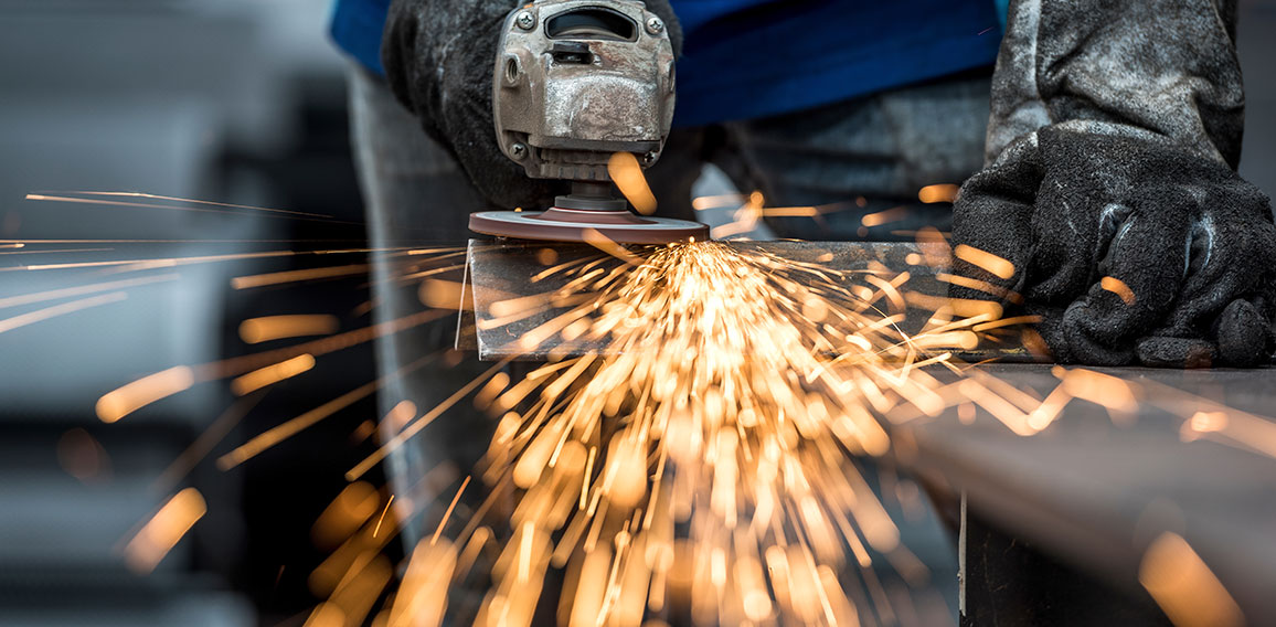 Industrial worker cutting metal with many sharp sparks