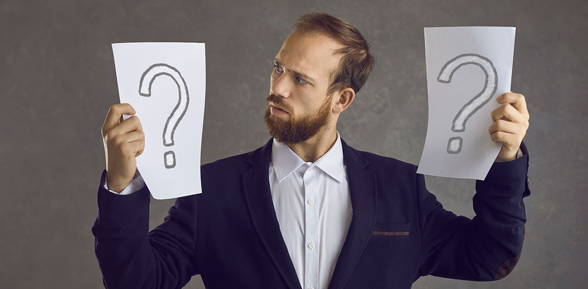 Puzzled businessman holding two question marks asking himself what decision to take