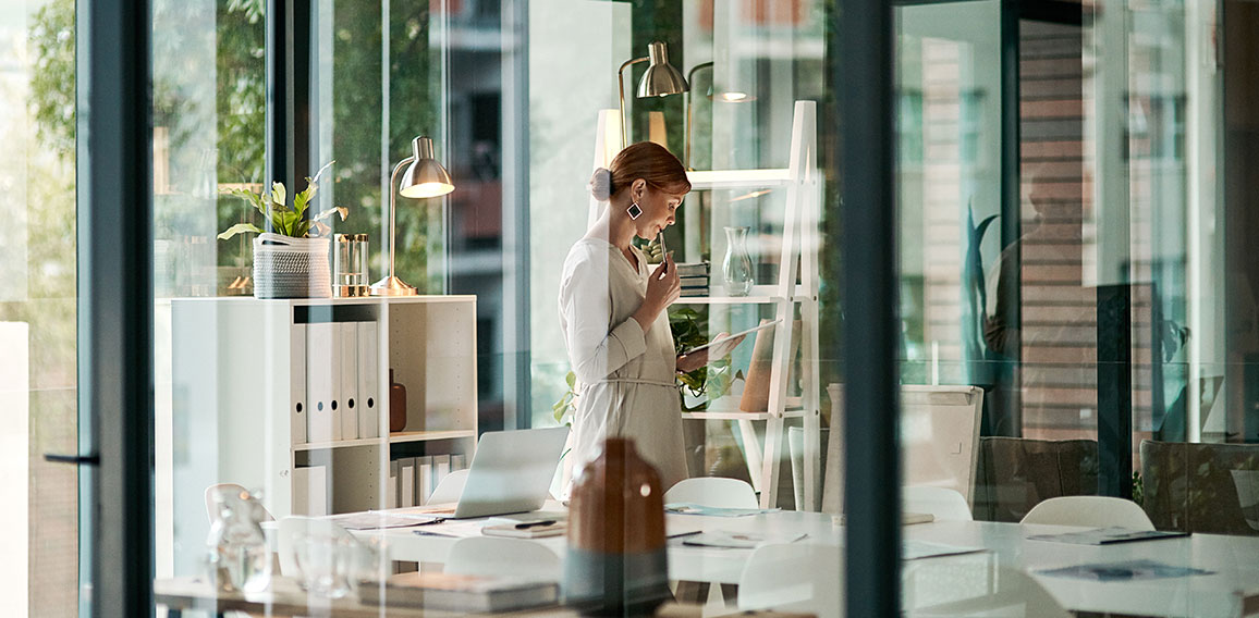 A modern office, building interior and a businesswoman doing online research on a tablet or looking at files. Female inside her corporate workplace architecture indoors preparing for a presentation.