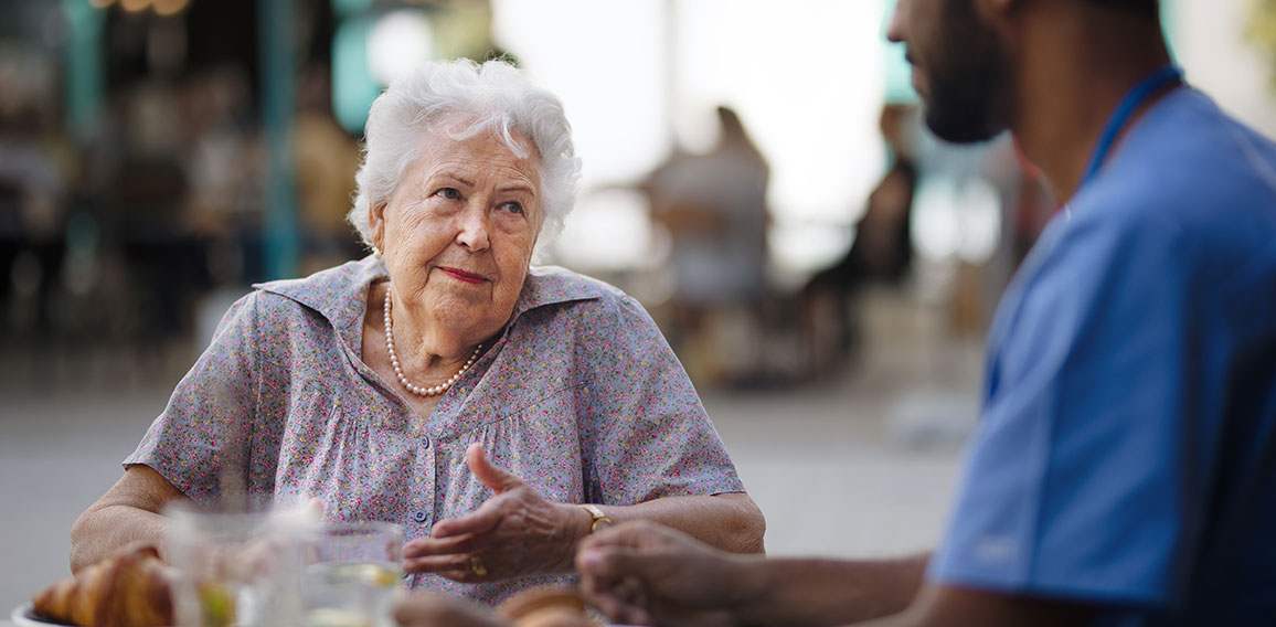 Caregiver having breakfast with his client at cafe.