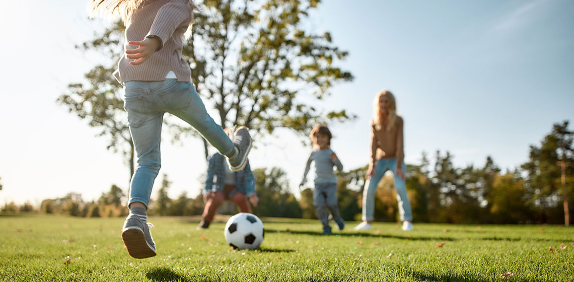 Where family fun begins. Happy family playing with a ball on meadow