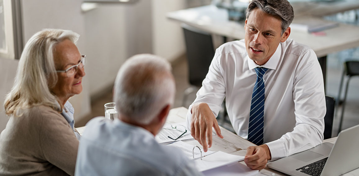 Insurance agent consulting senior couple about  their financial reports on a meeting.