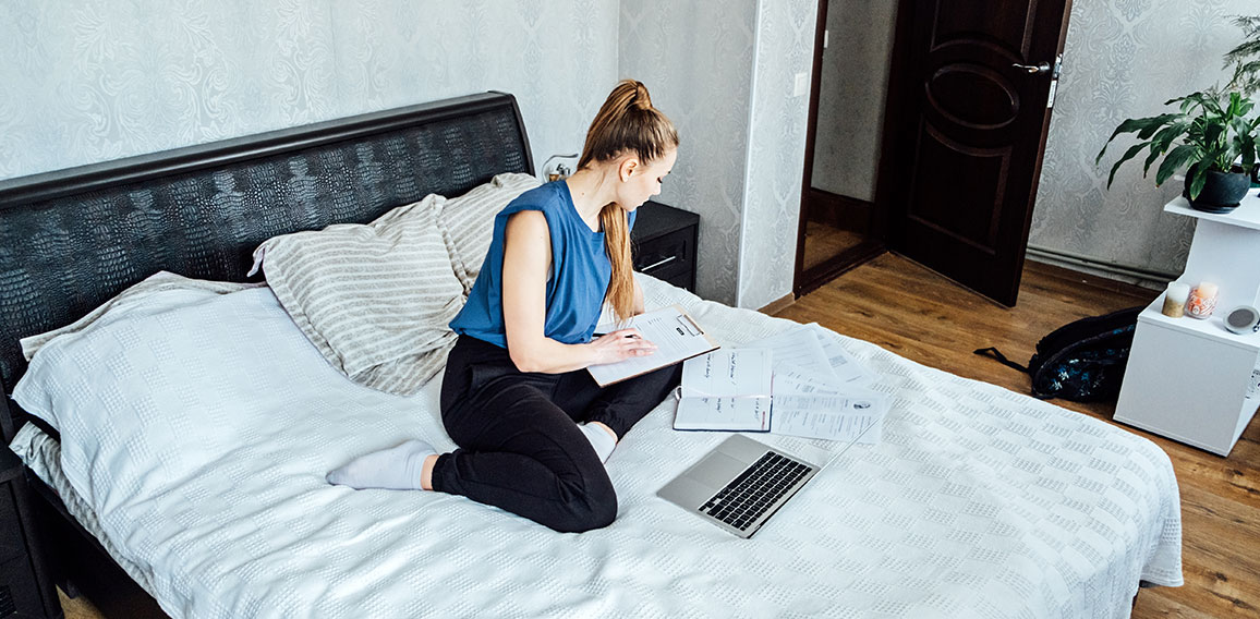 Job search concept, find your career. Young woman looking a job at online website by laptop computer sitting on bed at home.