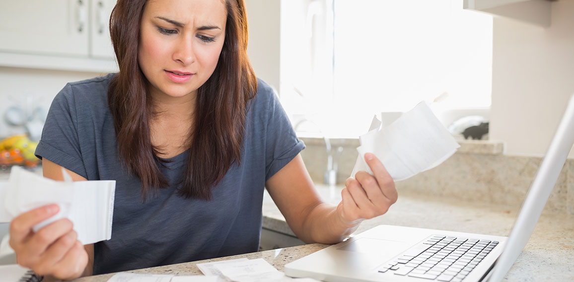 Young woman getting stressed over finances in kitchen