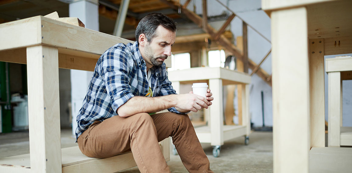 Sad carpenter drinking coffee