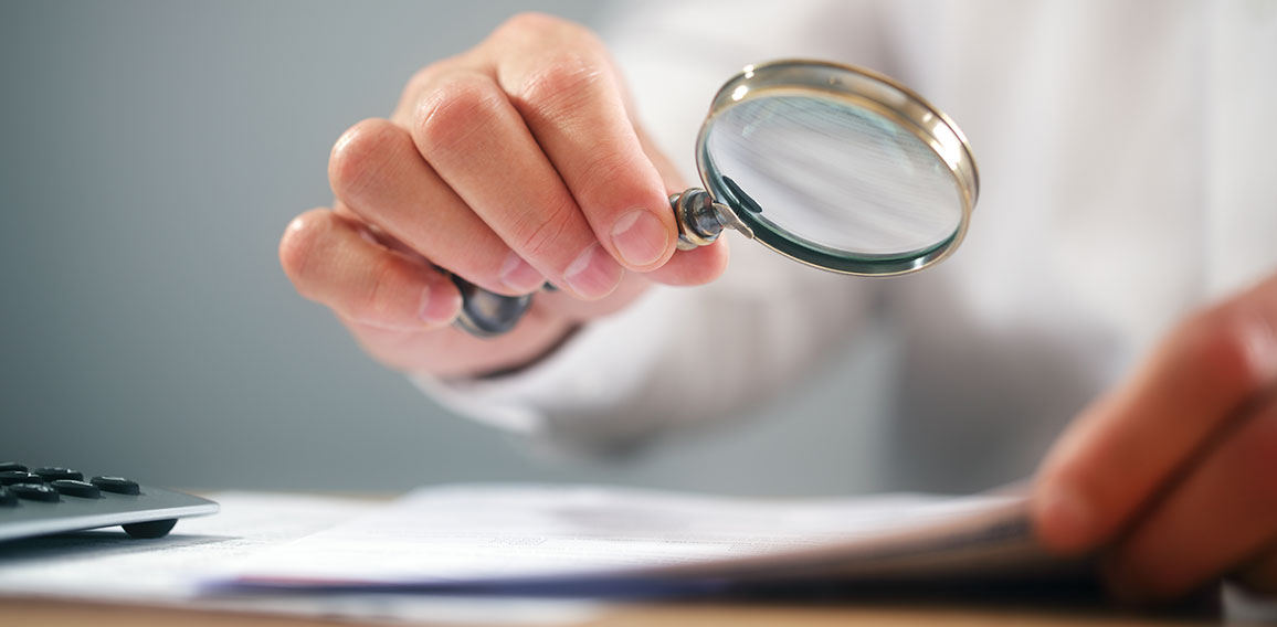 Businessman with magnifying glass reading documents