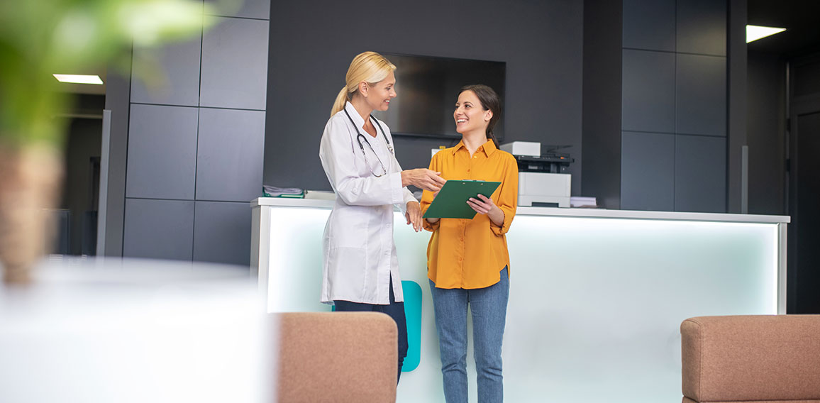 Blond doctor helping in white robe talking to patient