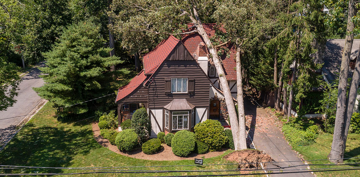 The aftermath of a dangerous wind in a suburb. A tree has fallen on a house in a small town in New Jersey after a storm and destroyed the roof.