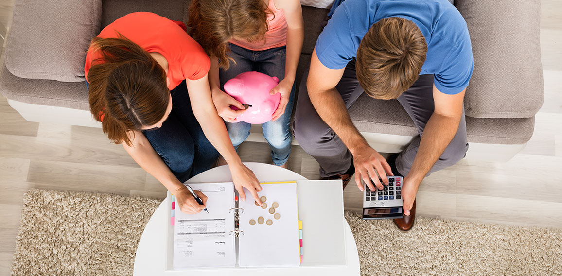 Family Sitting On Sofa Calculating Bill