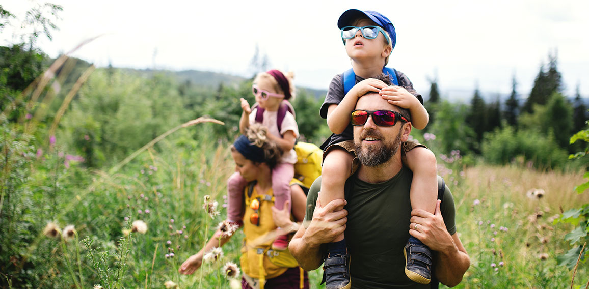 Family with small children hiking outdoors in summer nature.