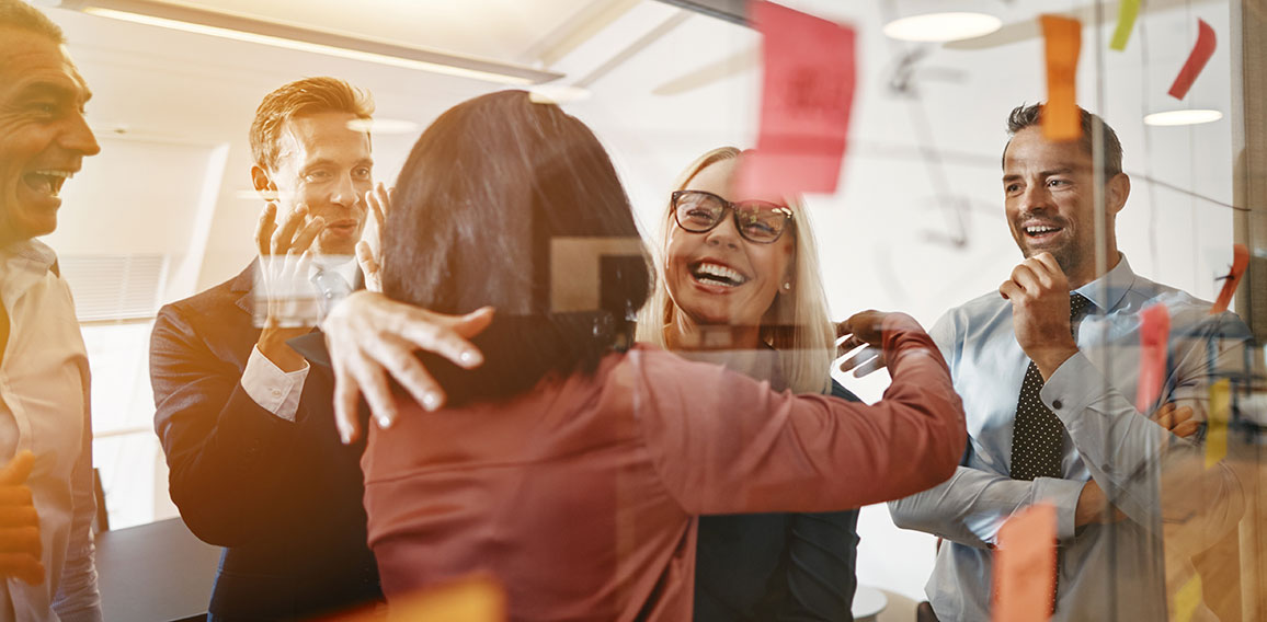 Businesswomen hugging while brainstorming with their team in an