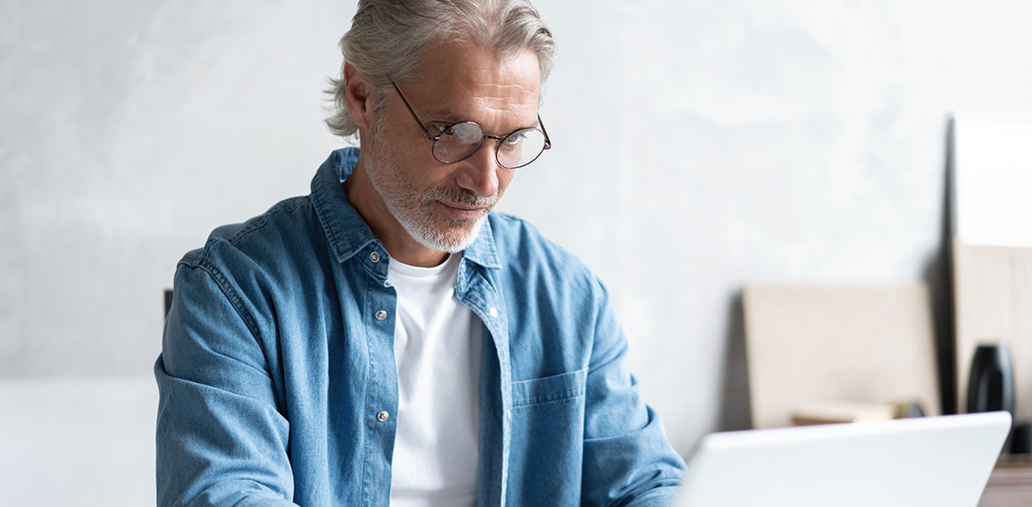 Middle-aged man working from home-office on laptop.