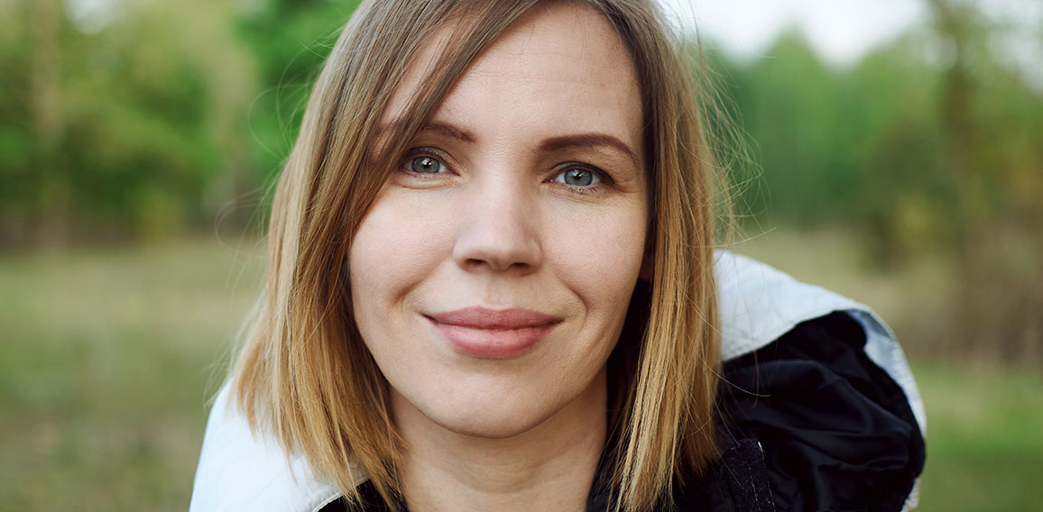 Middle-aged woman in a jacket on the street in the park.