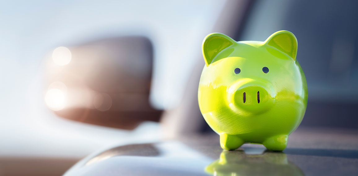 Green piggy bank money box on top of car hood, new vehicle purch