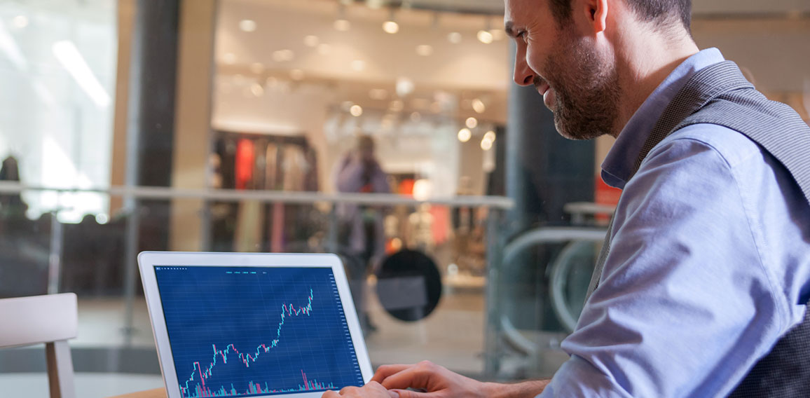 Investor analyzing stock market with charts on screen at restaur