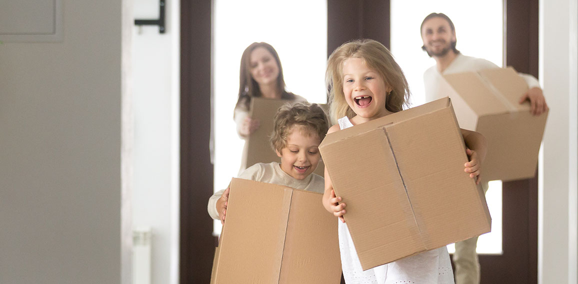 Couple and little kids with boxes running into new house