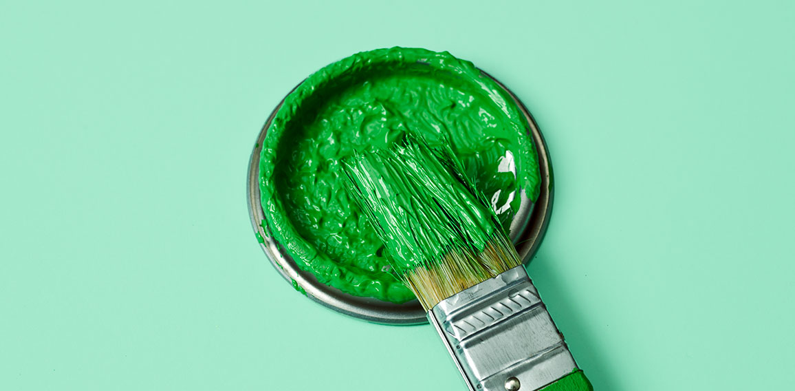 green paint in a paintbrush and lid of a paint can