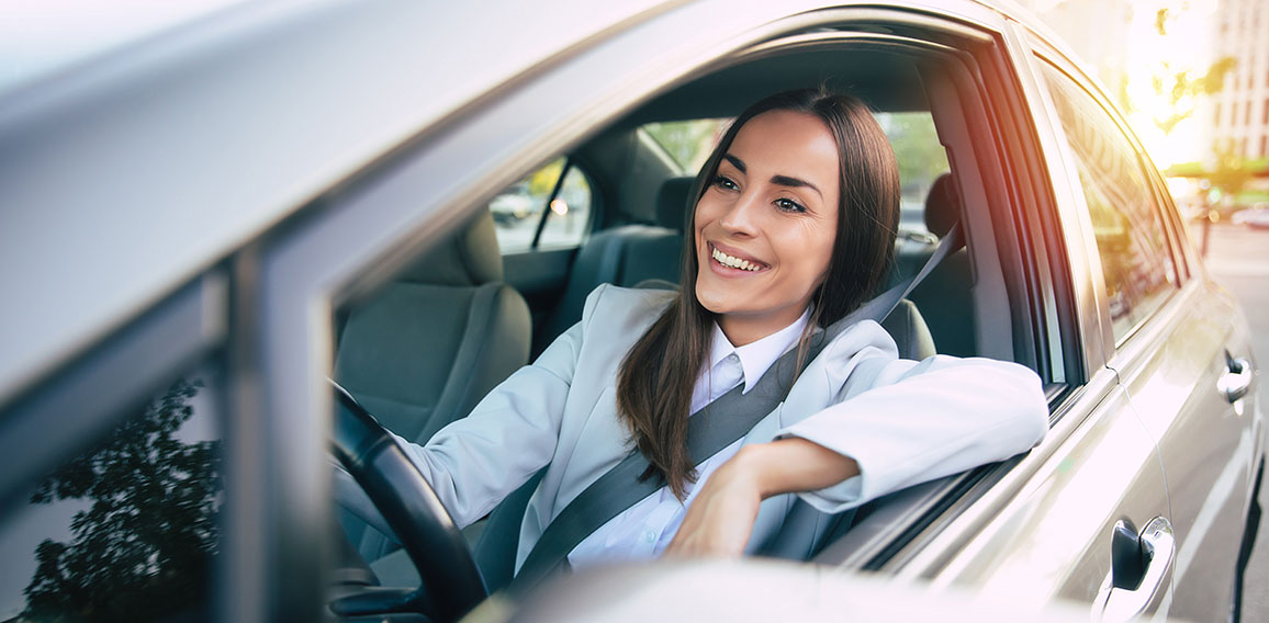 Portrait of cute female driver steering car with safety belt