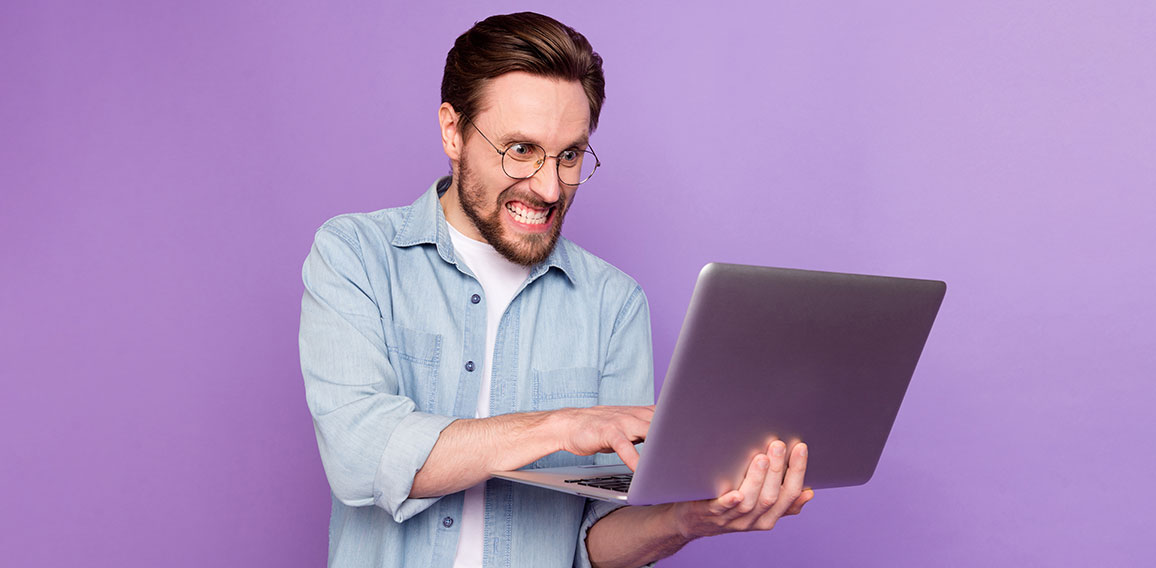 Photo of unhappy angry young man look hold laptop write letter work isolated on purple color background