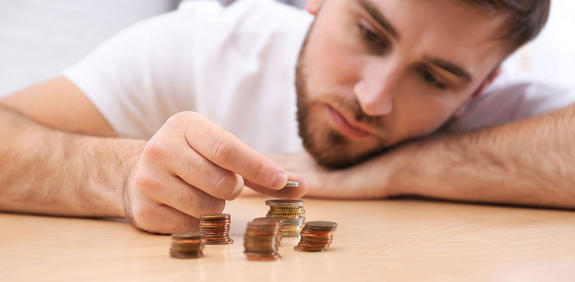 Sad young man counting money at home, closeup